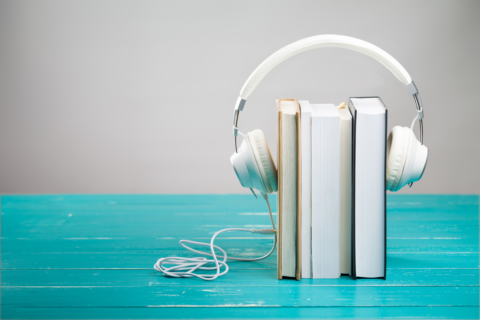Books and headphones on turquoise table in audiobook concept